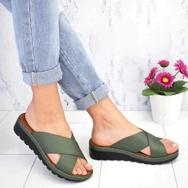 Grüne Damen-Sandalen mit Kreuzriemen, bequem, lässig, auf weißem Hintergrund mit Blumen.