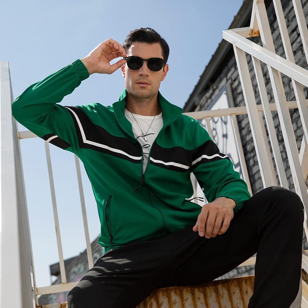 Mann in grüner Sportjacke mit Streifen, Sonnenbrille, sitzt auf Treppe, lässige Mode.