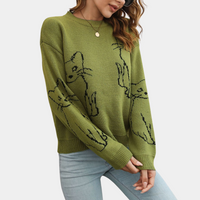 Frau trägt grünen Pullover mit Katzenmotiv, Rundhalsausschnitt, lässig, modisch, Damenmode.