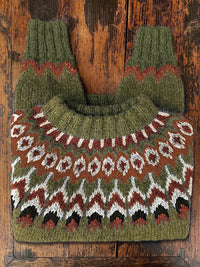 Grüner Norwegerpullover aus Wolle mit traditionellem Muster auf Holztisch.