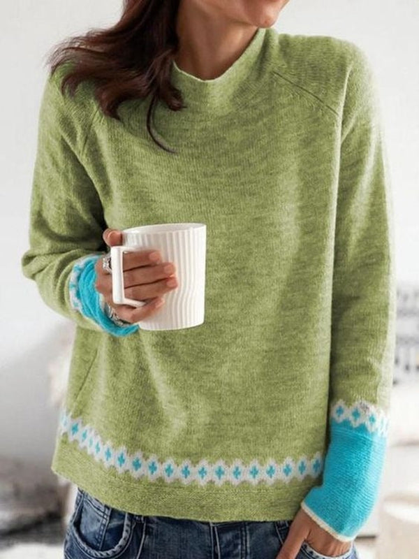 Frau in grünem Strickpullover mit blauem Muster hält weiße Tasse, lässige Mode.