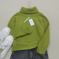 Grüner Rollkragenpullover aus Wolle, Damenmode, Herbst, neben weißen Sneakers und Jeans.