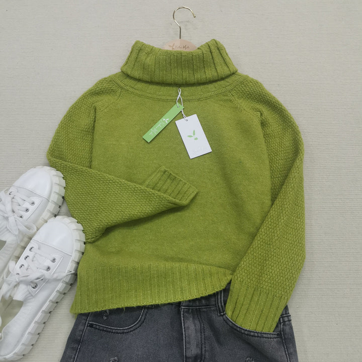 Grüner Rollkragenpullover aus Wolle, Damenmode, Herbst, neben weißen Sneakers und Jeans.