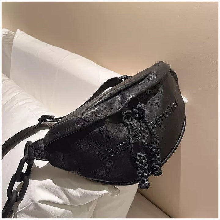 Schwarze Leder-Bauchtasche mit Kordelzug, modisch, auf weißem Sofa drapiert.