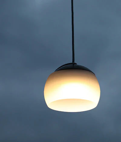 Hängelampe aus Glas, modern, weiß, beleuchtet, vor dunklem Himmel, Innenbeleuchtung.