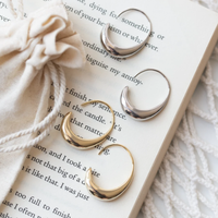 Silberne und goldene Creolen auf Buchseite, Schmuckbeutel, eleganter Modeschmuck.