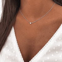 Silberne Halskette mit kleinem Anhänger, Damenmode, eleganter Schmuck, minimalistisches Design.