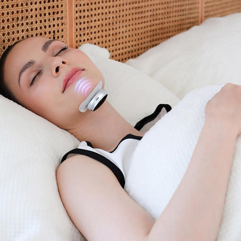 Frau mit Nackenmassagegerät im Bett, weiß, kabellos, Entspannung, Hautpflege, Wellness.