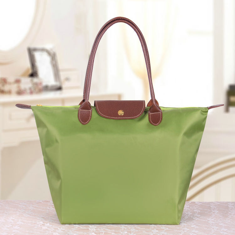 Grüne Handtasche aus Leder und Stoff, elegantes Design, ideal für Damenmode.