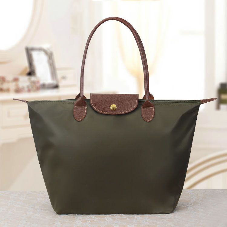 Grüne Damenhandtasche aus Leder und Nylon, elegant, mit braunen Griffen.