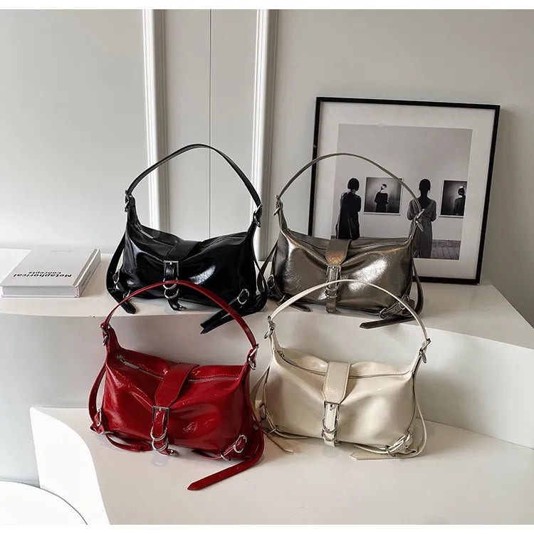 Vier modische Handtaschen aus Leder in Schwarz, Silber, Rot und Weiß auf einem Tisch.