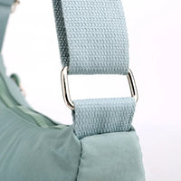 Hellblaue Umhängetasche aus Stoff mit verstellbarem Riemen und silberner Metallschnalle.