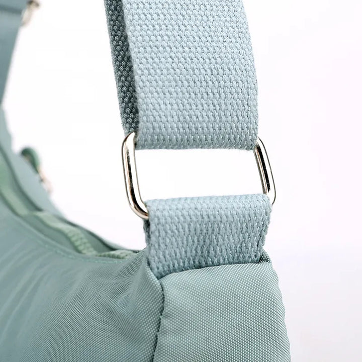 Hellblaue Umhängetasche aus Stoff mit verstellbarem Riemen und silberner Metallschnalle.