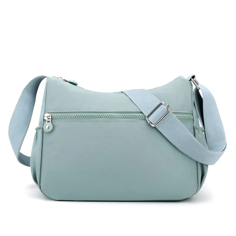 Hellblaue Umhängetasche aus Nylon mit verstellbarem Gurt und Reißverschluss, modisch und praktisch.