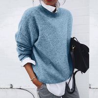 Frau in blauem Strickpullover, weißem Hemd, grauer Hose, schwarze Tasche, lässiger Stil.