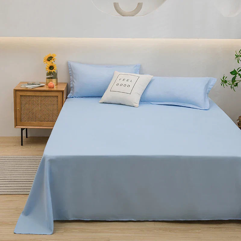 Bett mit hellblauer Bettwäsche, Kissen "Feel Good", Nachttisch mit Sonnenblumen, modernes Schlafzimmer.