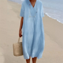 Frau im blauen Leinenkleid am Strand mit Strohtasche, Sommermode, lässiger Stil.