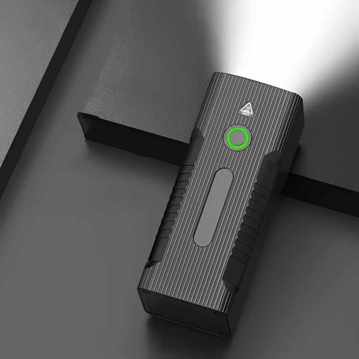 Schwarze LED-Taschenlampe mit grünem Knopf, leuchtend, auf grauem Hintergrund.