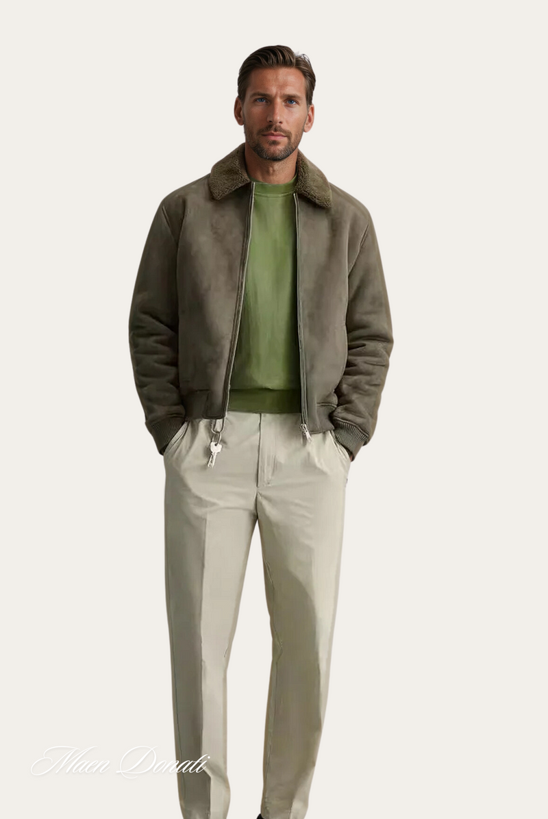 Mann in olivgrüner Bomberjacke mit Fellkragen, grünes Shirt, beige Hose, Mode Herrenbekleidung.