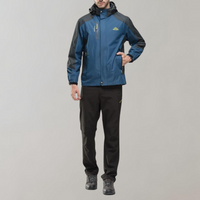 Mann in blauer Outdoor-Jacke und schwarzer Hose, wetterfest, sportlich, funktional.