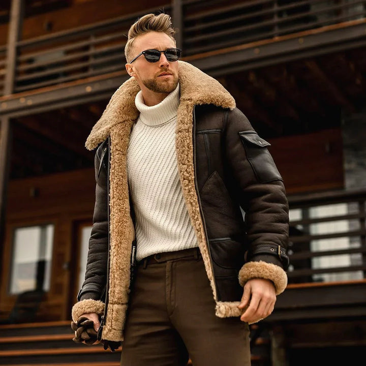 Mann in brauner, gefütterter Herren-Winterjacke, Wollpullover, Sonnenbrille, draußen.