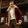 Mann in roter Herren-Winterjacke mit Fellfutter, weißem Rollkragenpullover, Sonnenbrille.