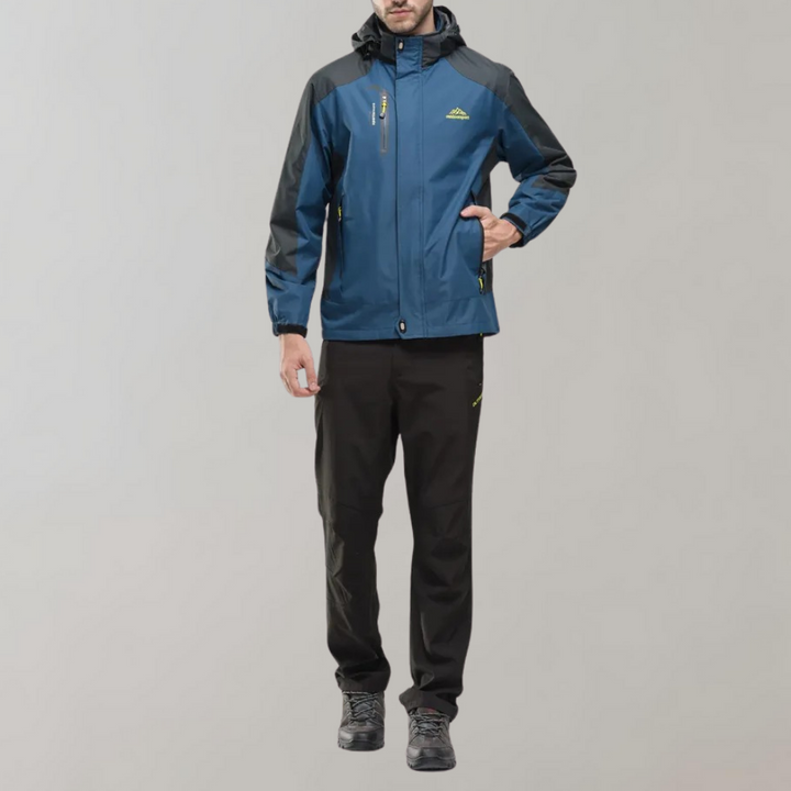 Mann in blauer Outdoor-Jacke und schwarzer Hose, wetterfest, sportlich, funktional.