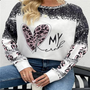 Frau trägt schwarz-weißes Sweatshirt mit Herz-Print und Leopardenmuster, lässige Mode.