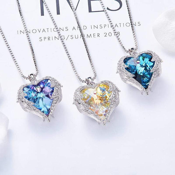 Drei Herzflügel-Halsketten mit Kristallen in Blau, Gelb und Lila auf weißem Hintergrund.