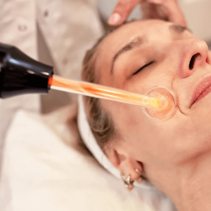 Frau bei Gesichtsbehandlung mit Hochfrequenzstab, Hautpflege, Anti-Aging, Wellness-Salon.