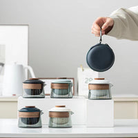 Moderne Teekannen aus Glas mit Holzdeckel, minimalistisch, auf weißem Hintergrund, Hand hält Tasche.