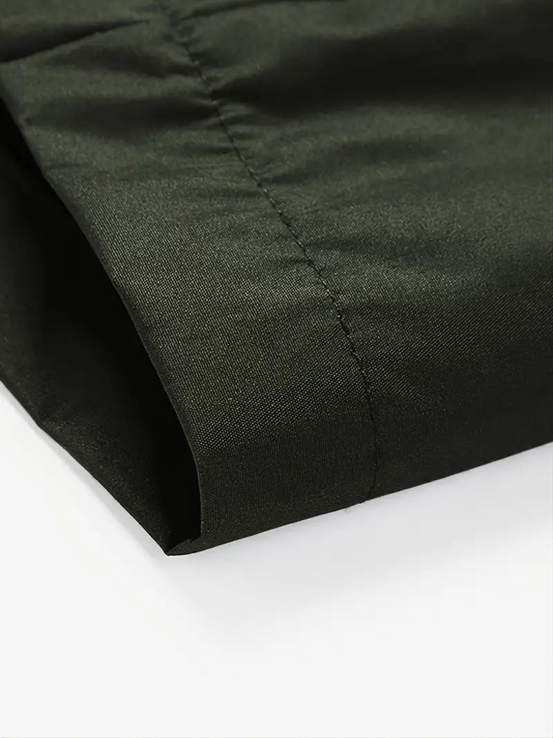 Dunkelgrüner Baumwollstoff, Nahaufnahme, glatte Textur, hochwertige Nähte, Mode-Design.