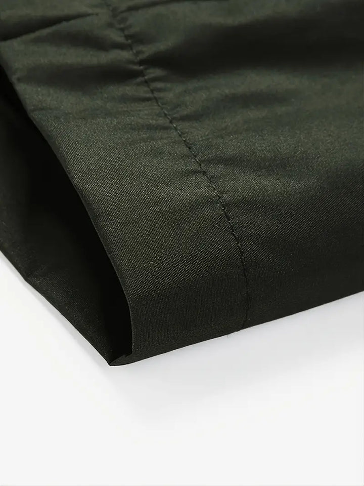 Dunkelgrüner Baumwollstoff, Nahaufnahme, glatte Textur, hochwertige Nähte, Mode-Design.