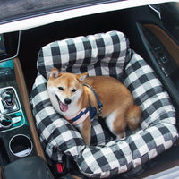 Shiba Inu Hund in kariertem Hundebett im Auto, bequem und sicher, Haustiertransport.