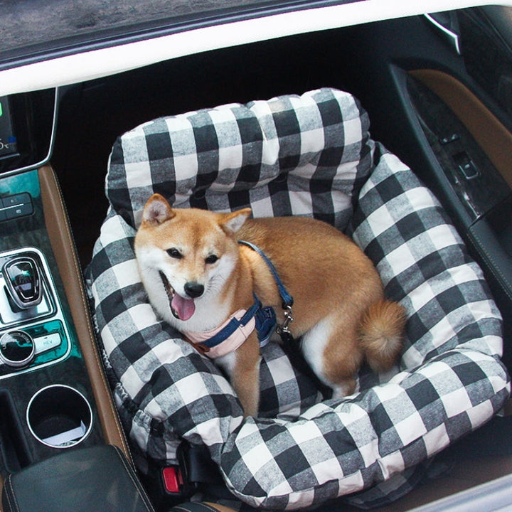 Shiba Inu Hund in kariertem Hundebett im Auto, bequem und sicher, Haustiertransport.