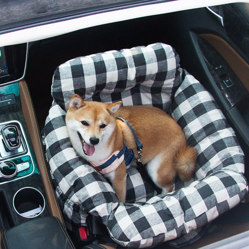 Shiba Inu Hund in kariertem Hundebett im Auto, bequem und sicher, Haustiertransport.