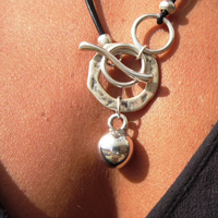 Silberne Halskette mit rundem Anhänger, Lederband, modisches Schmuckstück, Nahaufnahme.