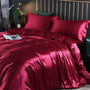 Rotes Seidensatin-Bettwäsche-Set auf Doppelbett, luxuriös, elegant, Schlafzimmer-Dekor.