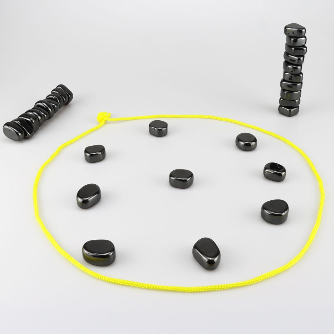 Schwarze Steine im Kreis mit gelbem Seil, auf grauem Hintergrund, Meditations-Set.