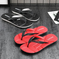 Schwarze und rote Japsom Flip-Flops aus Gummi auf grauem Boden, ideal für Sommer und Strand.
