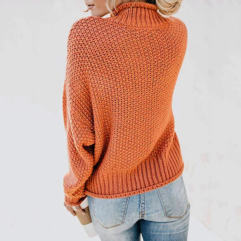 Frau in orangefarbenem Strickpullover und blauer Jeans, Rückansicht, lässige Herbstmode.