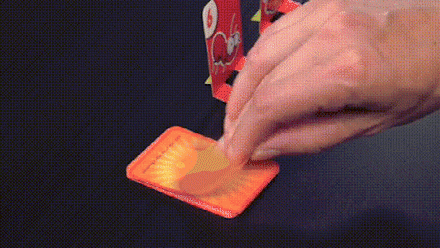 Hand legt Karte auf Tisch, rotes Kartenspiel, Brettspiel, Strategie, Unterhaltung, Familienaktivität.