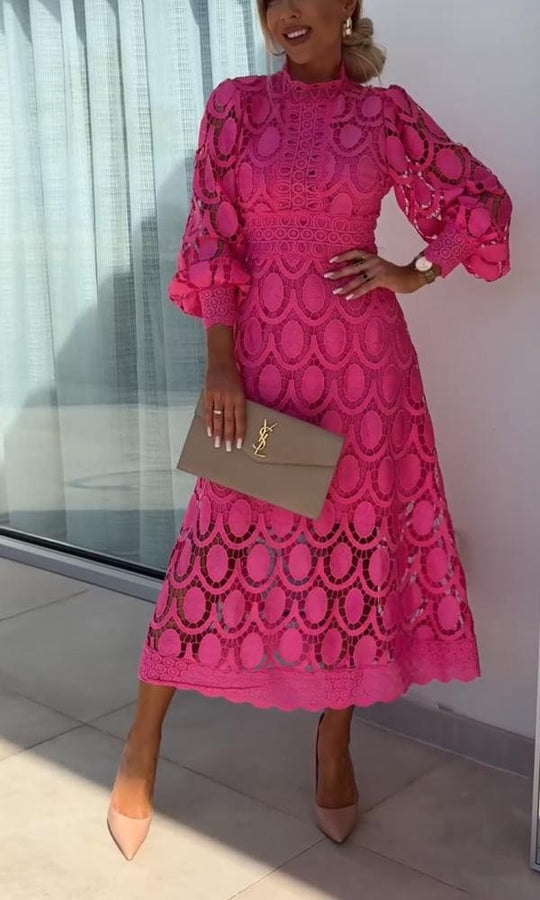 Frau in rosa Spitzenkleid mit langen Ärmeln, hält eine beige Designer-Clutch, elegante Mode.