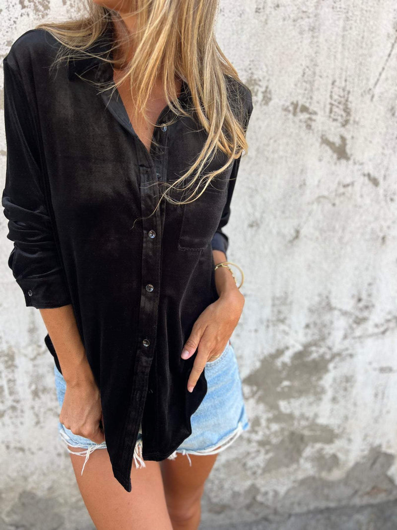 Frau in schwarzem Hemd und Jeansshorts vor Betonwand, lässiger Sommerlook, Modefotografie.