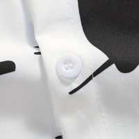 Weiße Hemdknopf-Detailaufnahme, schwarzes Muster, glattes Gewebe, modisches Design.