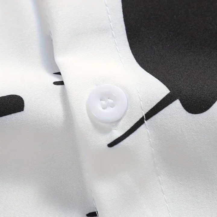 Weiße Hemdknopf-Detailaufnahme, schwarzes Muster, glattes Gewebe, modisches Design.