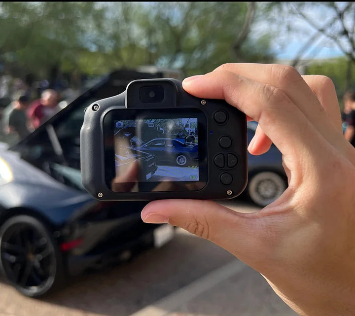 Person hält Kamera, fotografiert schwarzes Auto, Outdoor, sonniger Tag, Nahaufnahme.