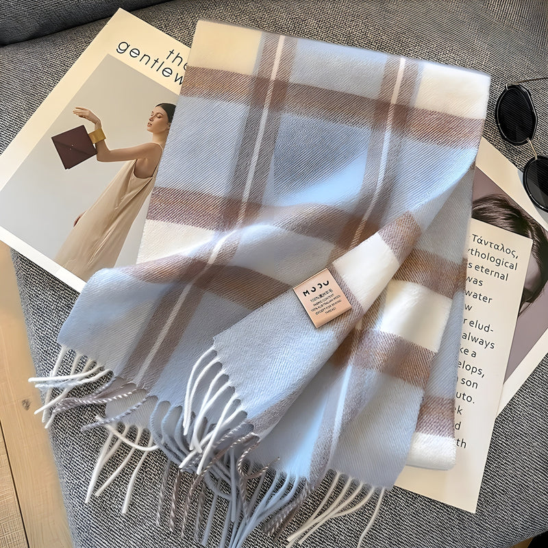 Kariertes Kaschmirschal in Weiß und Beige auf grauem Sofa, modisches Accessoire.