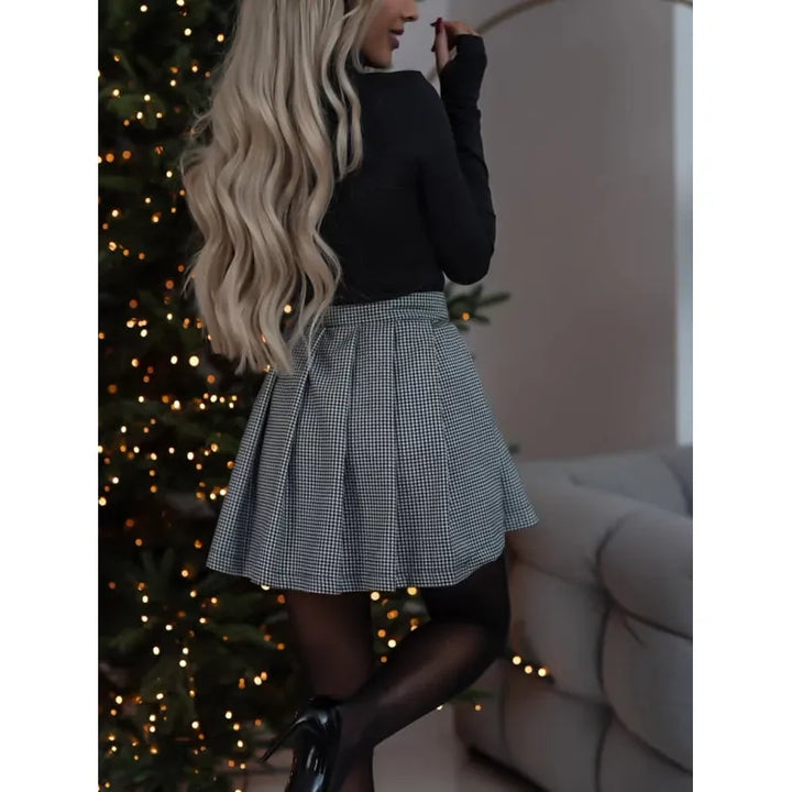 Frau in kariertem Rock vor Weihnachtsbaum, elegante Mode, zeitloser Stil, festliche Kleidung.