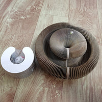 Brauner Katzenkratzer aus Wellpappe auf Holzboden, Spielzeug inklusive.